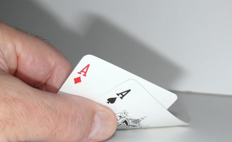 A hand peeking two aces of poker cards