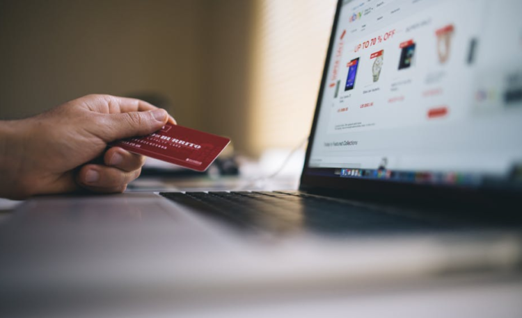 A hand holding a card right next to a laptop